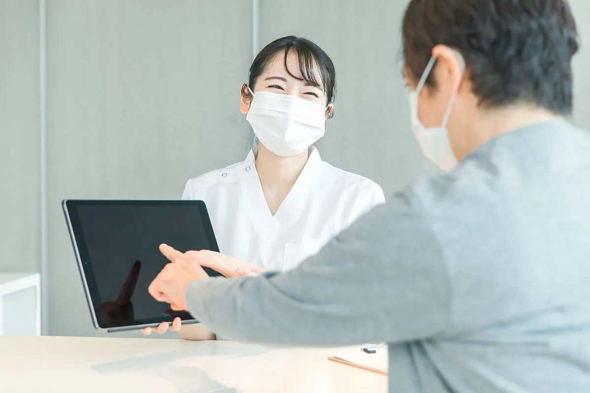 患者にタブレットを見せる女性