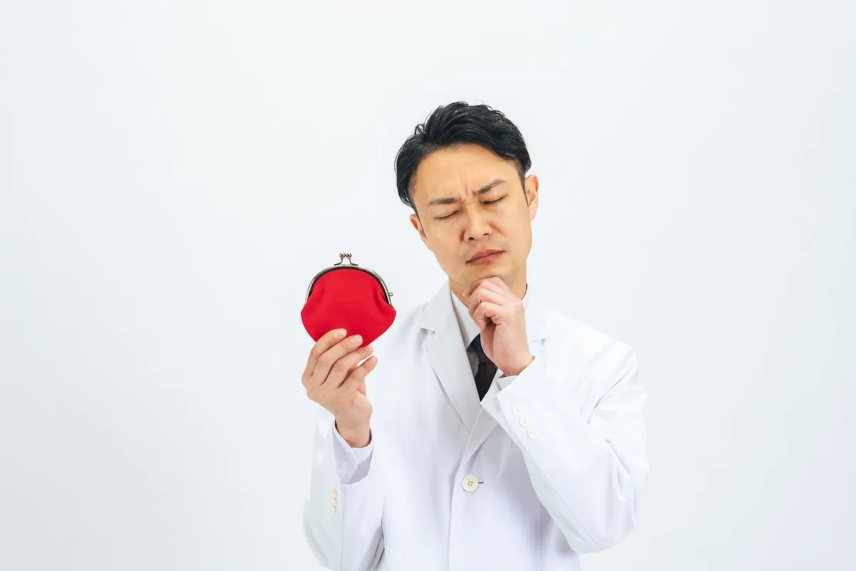 赤いがま口財布を持つ白衣を着た男性
